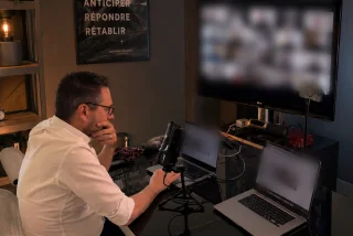 Le studio pendant un direct : Vincent Ottinger de dos à son bureau, micro en place, face à un écran où une vingtaine de participants sont connectés.